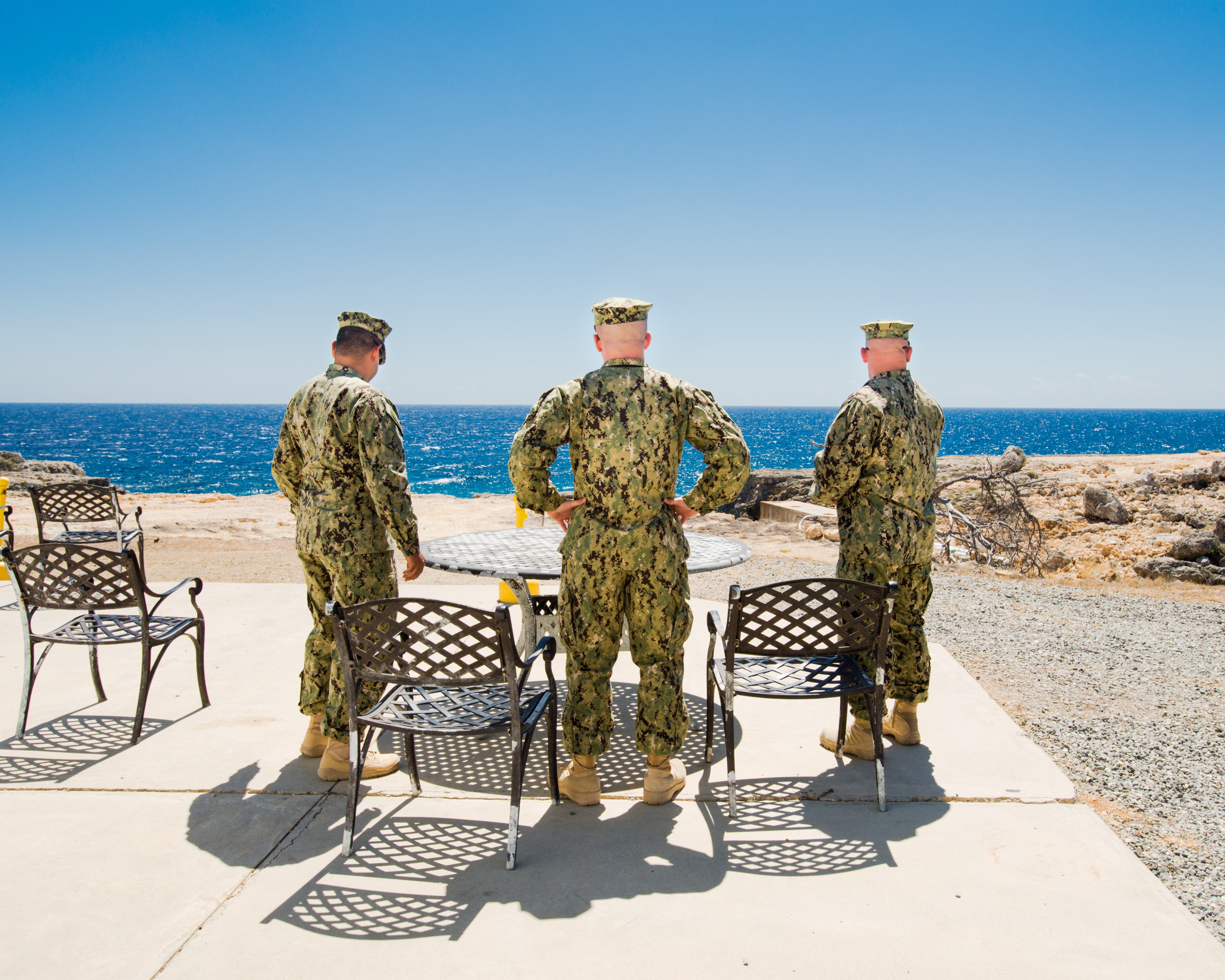 Drei Soldaten bei der Zigarettenpause, von hinten fotografiert, mit Blick aufs Meer. (c) Debi Cornwal