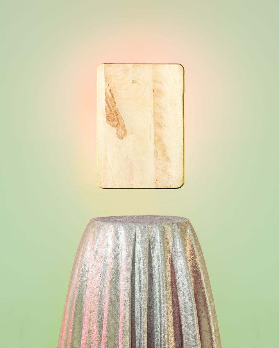 Bild mit lindgrünem Hintergrund. Unten ein runder Stehtisch mit silbrig glänzendem Überwurf, an der Wand in rosa Corona der "harmonie engergie transformer" - ein Schneidebrett. Foto: Klaus Pichler