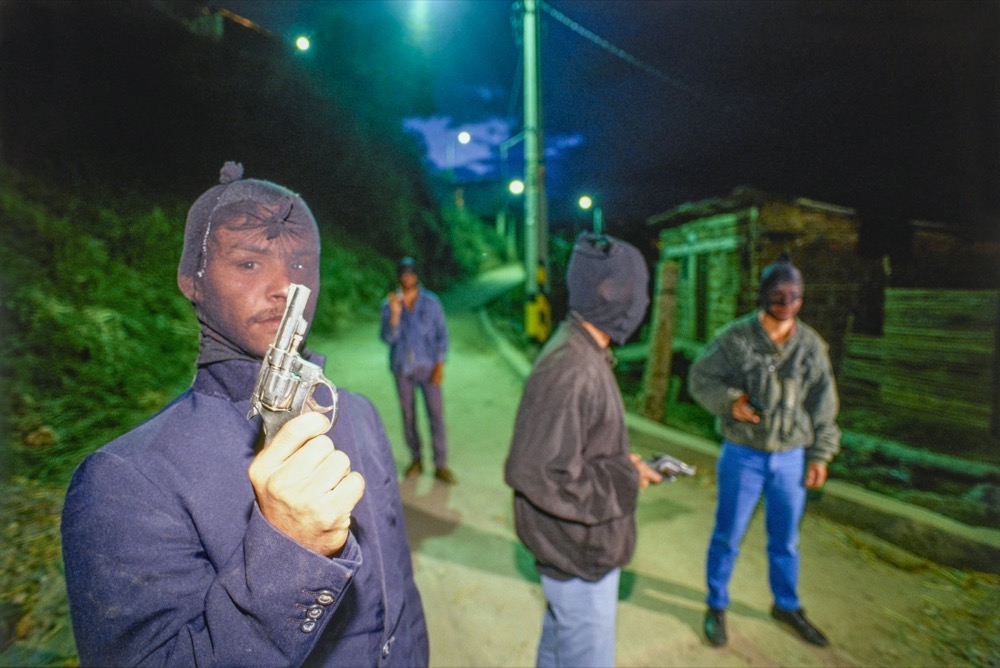 Mann mit Strumpfmaske und Waffe, im Hintergrund drei weitere Männer mit Strumpfmaske