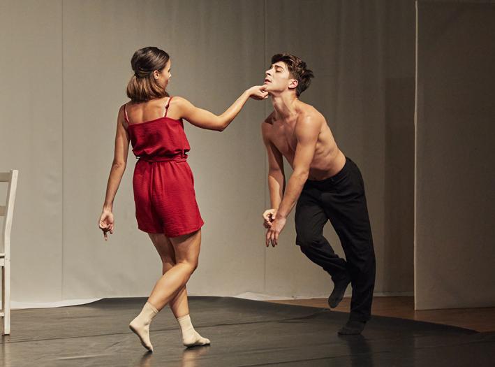 Szene aus der Tanzperformance Romeo und Julia...und wenn sie nicht gestorben sind. Zwei Tänzer, eine junge Frau in kurzer roter Bekleidung, berührt einen jungen Mann, mit freiem Oberkörper, am Kinn.